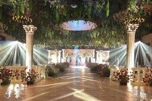 An indoor venue with a central aisle, columns, and floral arrangements. - Huaqiao Hotel (Yingtan)