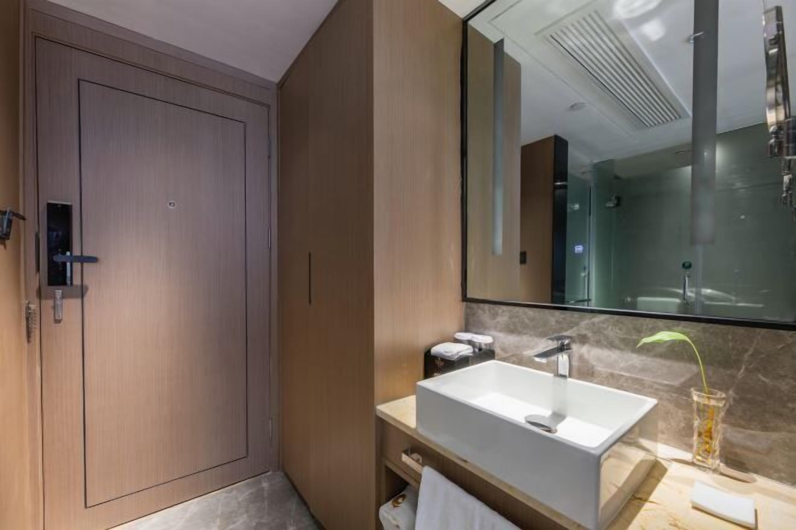 Un baño moderno con un espejo grande, un lavabo blanco y una zona de ducha.