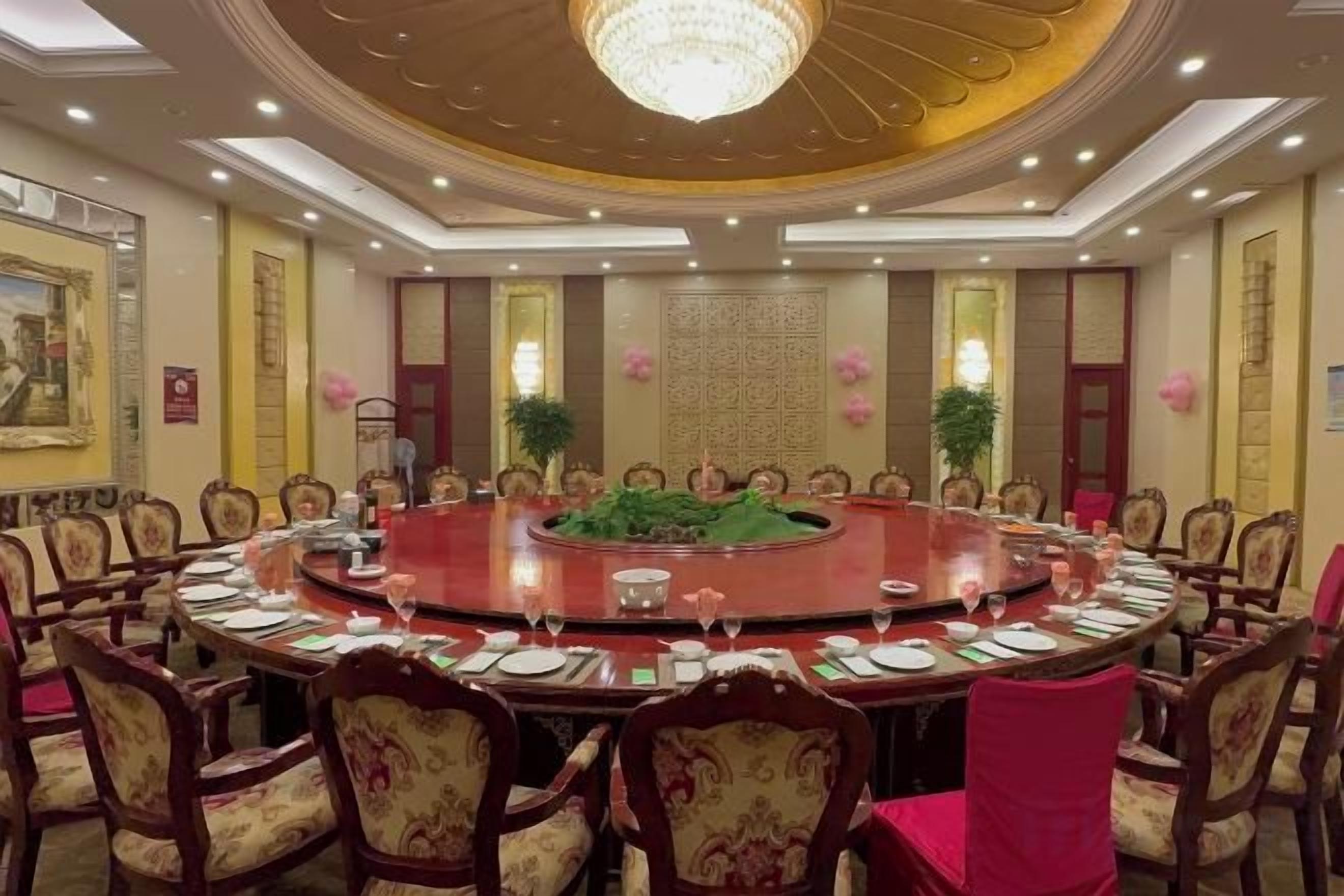 A conference room with a round table surrounded by chairs, a chandelier, and decorative elements.