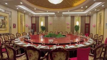 A conference room with a round table surrounded by chairs, a chandelier, and decorative elements.