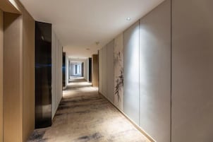 A long, narrow hallway with a wooden floor and a wall with a bamboo design.