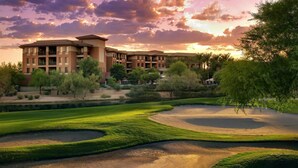 Un campo de golf con búnkeres y un edificio de varios pisos y balcones.