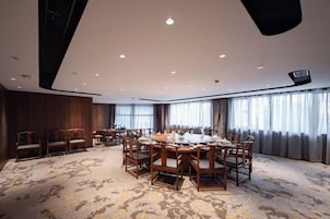Un salón de conferencias con una mesa redonda, varias sillas y piso alfombrado.