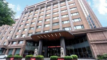 A multi-story hotel with a modern facade, large windows, and a prominent entrance with a covered area and statues.
