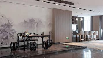 Un moderno vestíbulo de hotel con zona de comedor, un gran mural en la pared y un bar.