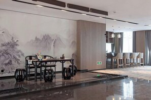 Um saguão de hotel moderno com área de refeições, um grande mural e um bar.