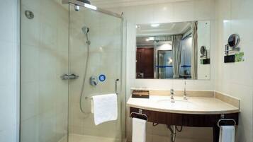 A modern bathroom with a glass-enclosed shower, a vanity with a sink, and a mirror above the sink.