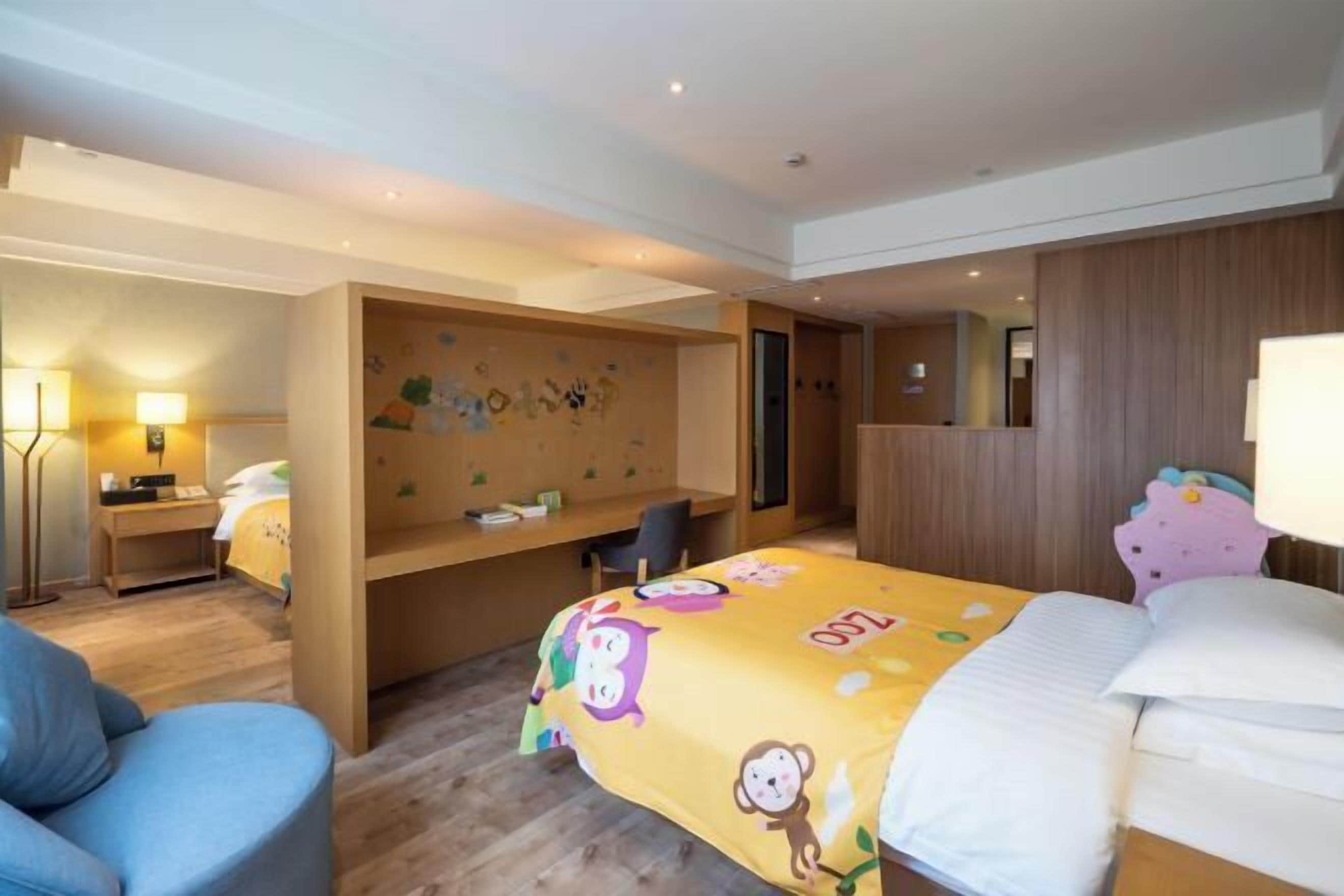 A hotel room with a bed, a desk, a chair, and a wall with a decorative mural.