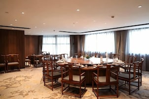 Un salón de conferencias con una mesa redonda, varias sillas y piso alfombrado.