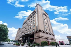 Un hotel grande de varios pisos con una entrada destacada y un cielo despejado al fondo.