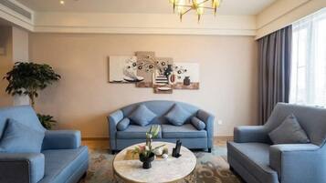 A living room with a sofa, two armchairs, a coffee table, and a chandelier.