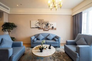 Una sala de estar con un sofá, dos sillones, una mesa de centro y una araña.