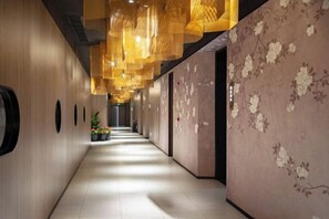 A corridor with a wooden wall, a floral wallpapered wall, and hanging lights. - Shengxiao Grand Hotel (Quzhou Airport) (Quzhou)