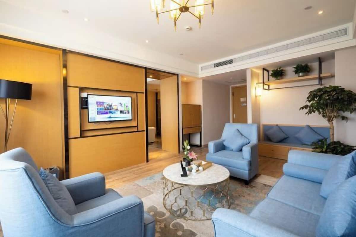 A modern living room with a flat-screen TV, blue sofas, a coffee table, and a chandelier.