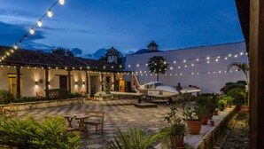 A courtyard with a plane, string lights, and potted plants. - Lemon Tree Hostel (Antigua Guatemala)