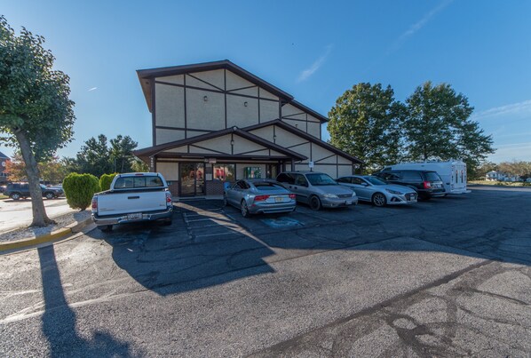 A parking lot with several cars and a building with a modern design. - Patuxent Inn (La Plata)