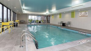 Una piscina interna con acqua cristallina, sedie gialle e un cartello che indica divieto di tuffi e assenza di bagnino.
