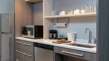 Een moderne keuken met een ingebouwde magnetron, koffiezetapparaat en een spoelbak.