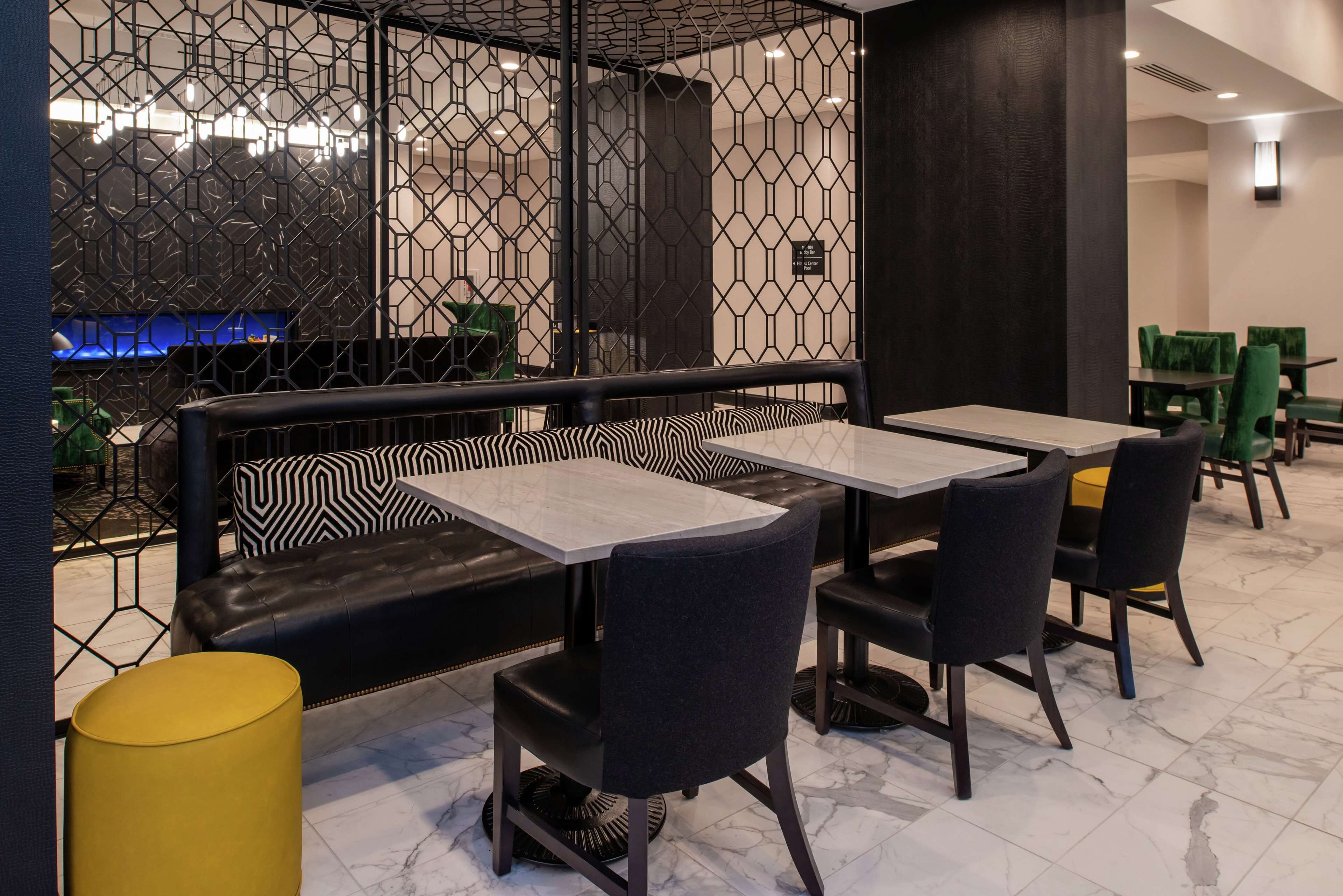 Un restaurant au décor moderne, avec un banc à motifs noir et blanc, des chaises sombres et un sol en marbre.