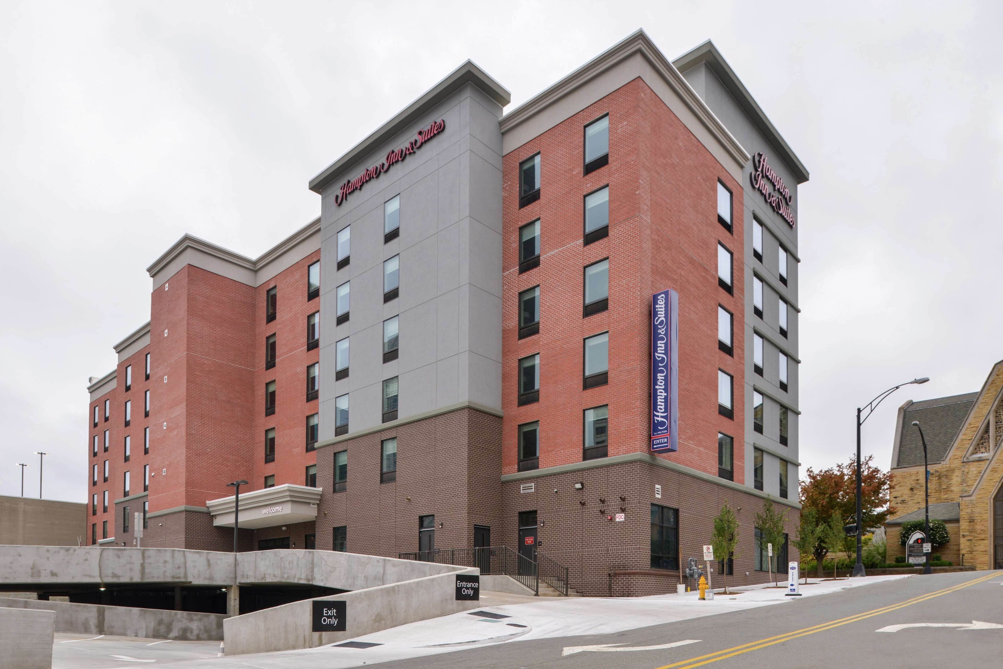 A multi-story hotel with a brick facade, multiple windows, and a sign indicating 'Welcome' at the entrance.
