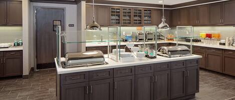 A modern kitchen with a central island, glass display case, and dark wood cabinets.