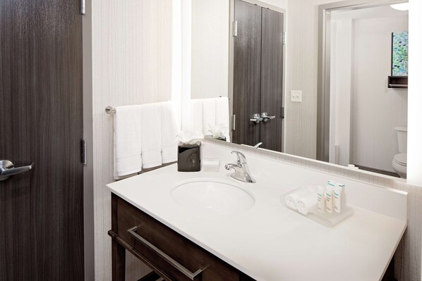 A modern bathroom with a white sink, dark wood vanity, and a large mirror.