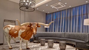 Une chambre d’hôtel moderne avec un grand canapé, une sculpture de taureau décorative et un parquet à motifs en chevrons.