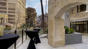 Une terrasse sur le toit, avec des tables et des chaises, des murs en pierre et une vue sur les bâtiments environnants.