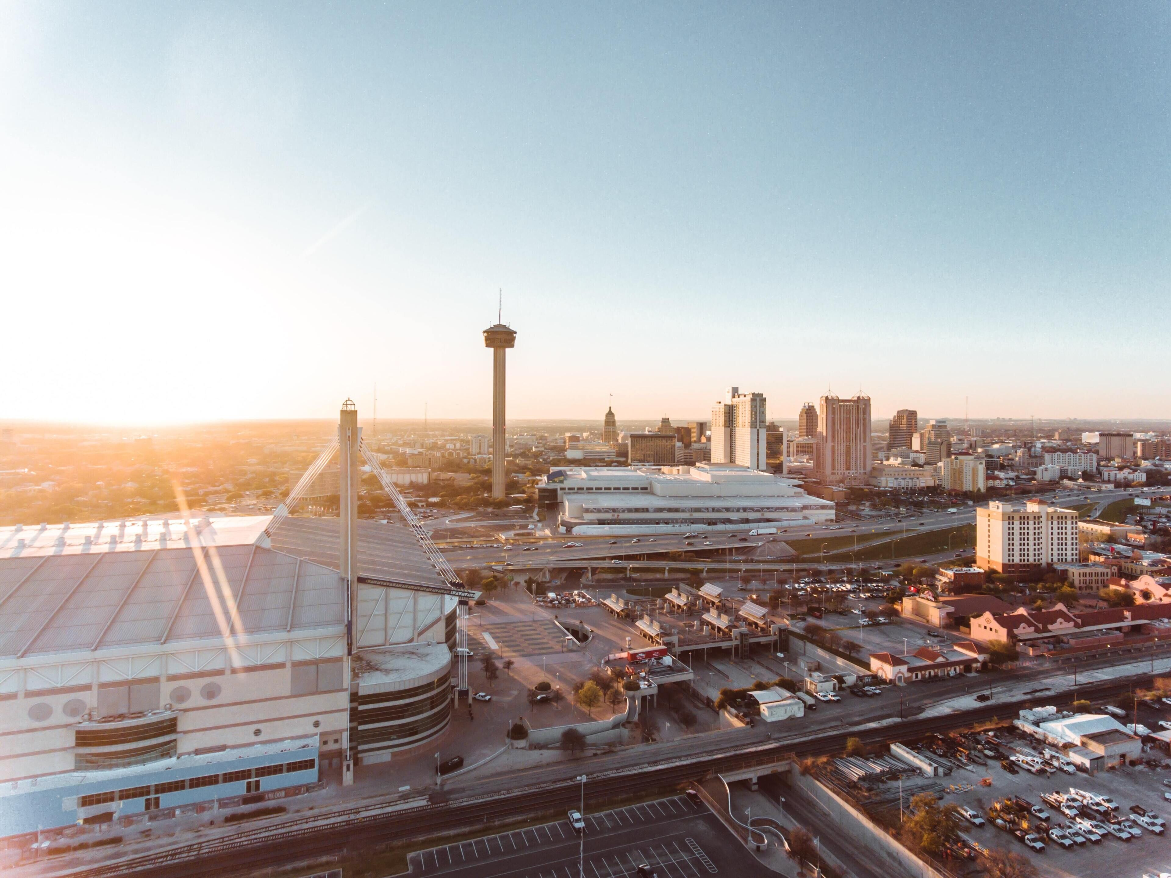 An aerial view of a cityscape with a prominent tower, stadium, and surrounding buildings.