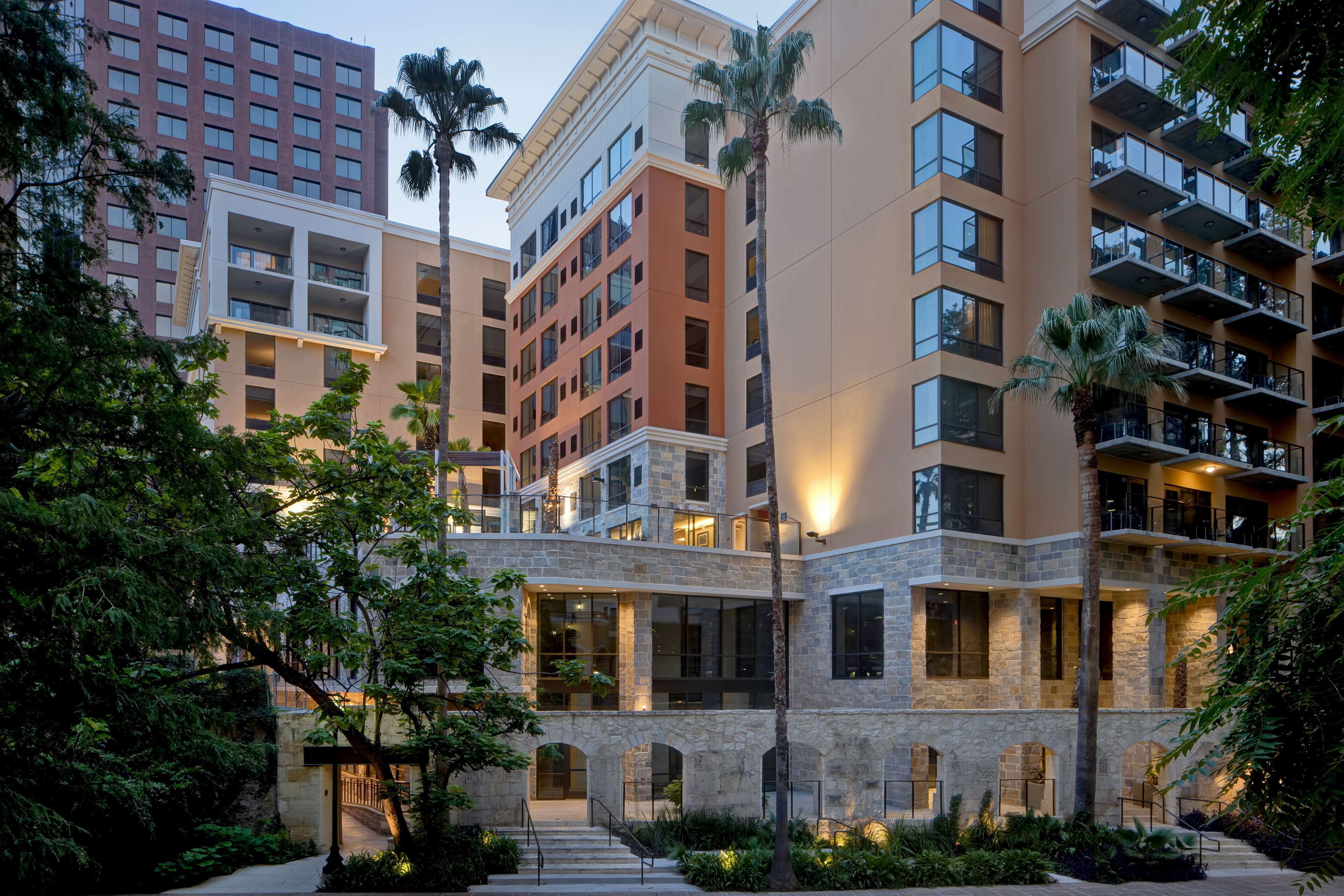 A multi-story hotel with balconies, stone facade, and a central courtyard with stairs.