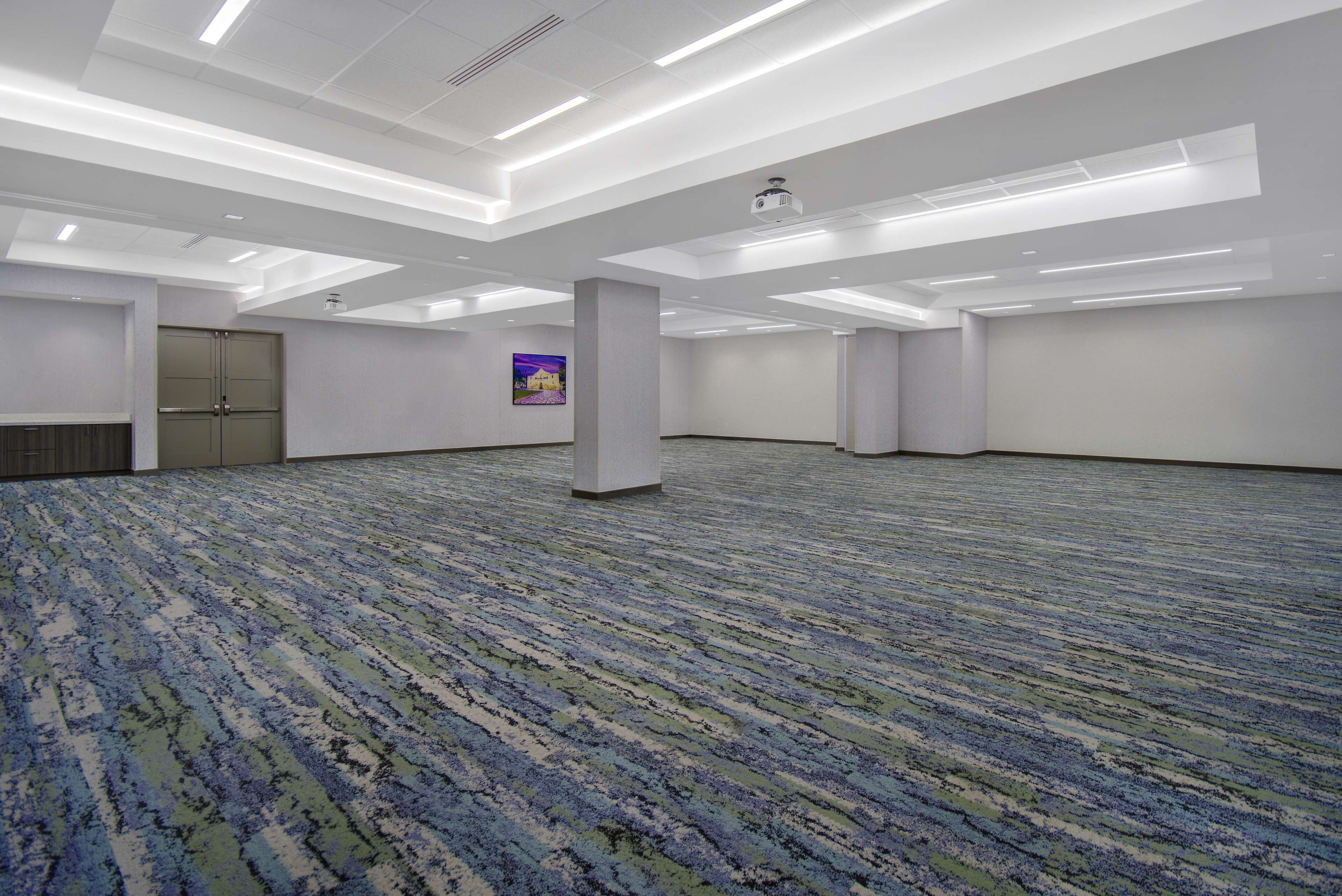 A large, empty conference room with a patterned carpet, white walls, and a ceiling with recessed lighting.