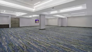 A large, empty conference room with a patterned carpet, white walls, and a ceiling with recessed lighting.