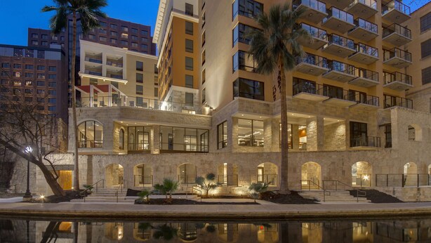 Un hôtel à plusieurs étages doté d’une piscine à effet miroir, d’une façade en pierre et de balcons.
