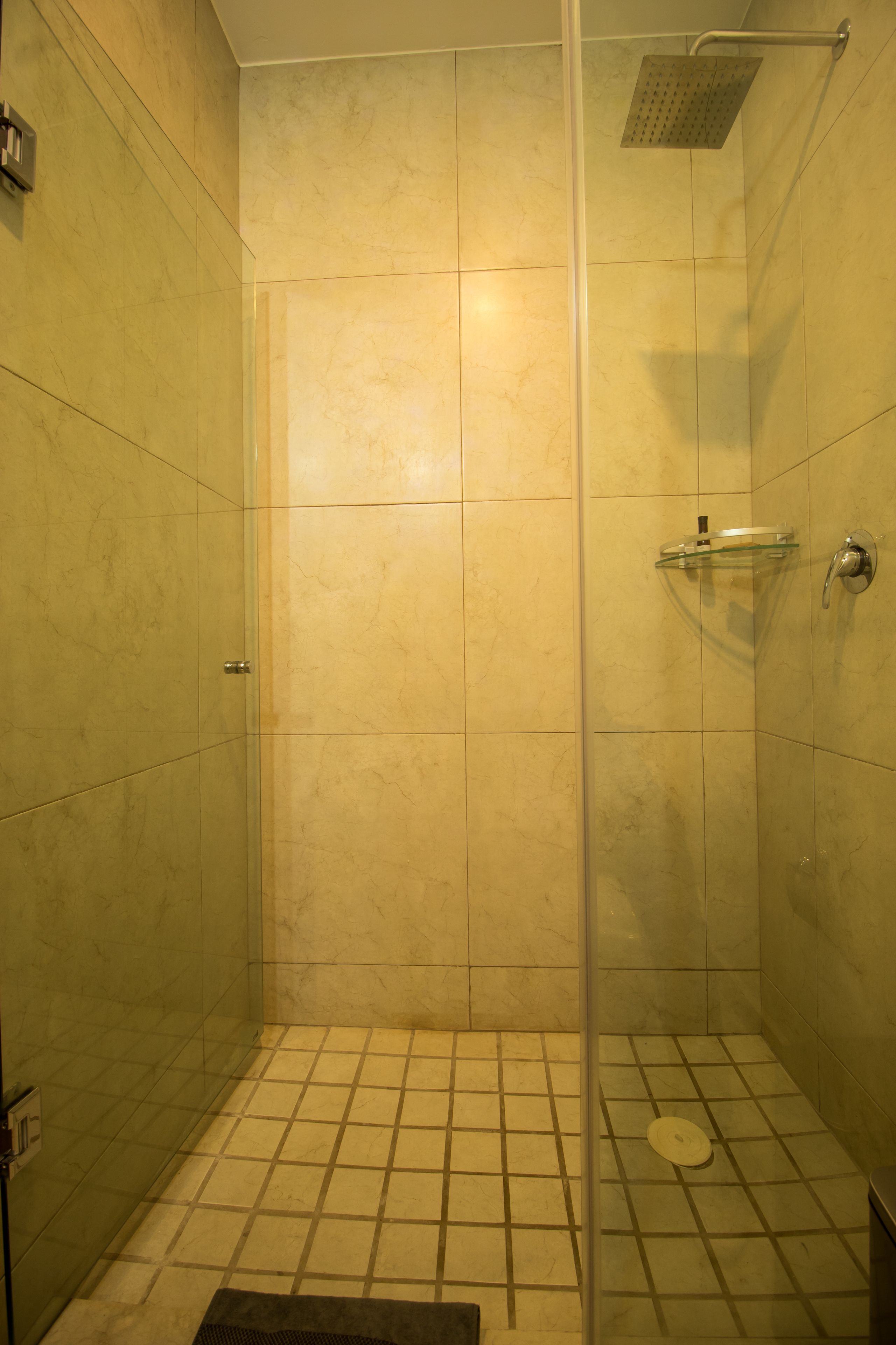 A small, enclosed shower area with a glass door, tiled walls, and a showerhead.