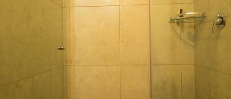 A small, enclosed shower area with a glass door, tiled walls, and a showerhead.