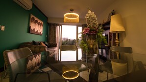 A modern living room with a glass dining table, chairs, a chandelier, and a large window with a view. - Niza Five Luxury Beach Apartments (Puerto Vallarta)
