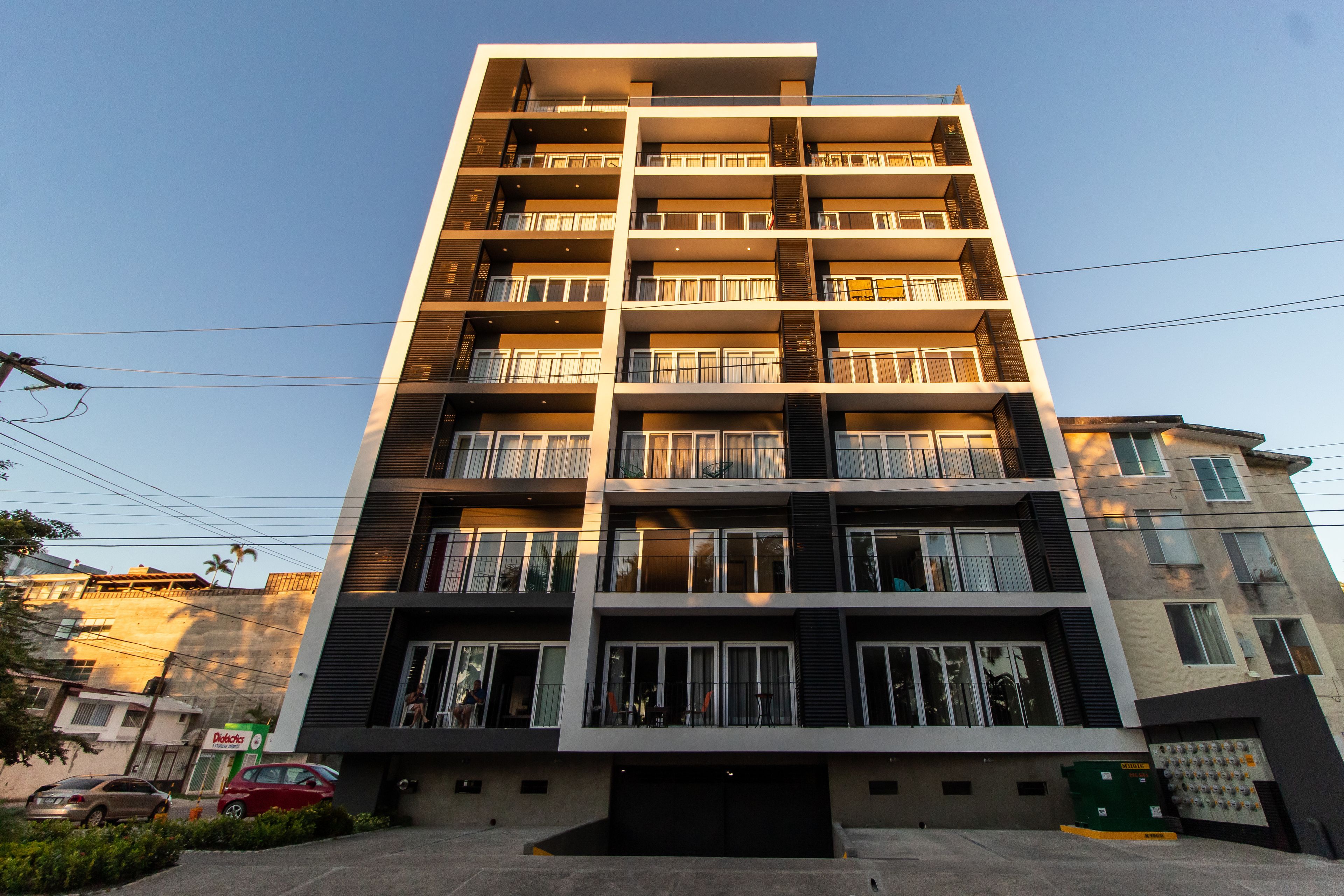 Un immeuble résidentiel à plusieurs étages, doté de balcons, d’un garage et d’une entrée bien visible.