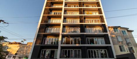 Un edificio residencial de varios pisos con balcones, garaje y entrada visible.