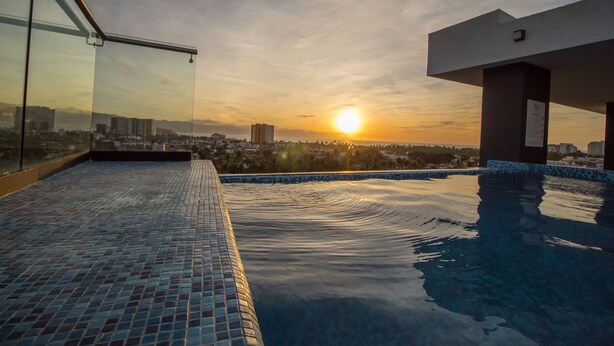 A rooftop infinity pool with a cityscape view at sunset. - Niza Five Luxury Beach Apartments (Puerto Vallarta)