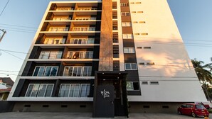 A multi-story building with a modern design, featuring balconies on each floor and a prominent entrance with a sign. - Niza Five Luxury Beach Apartments (Puerto Vallarta)