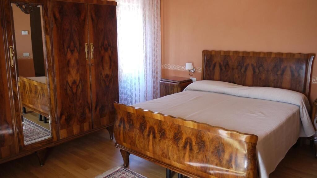 A bedroom with a wooden bed, a wardrobe, and a mirror.