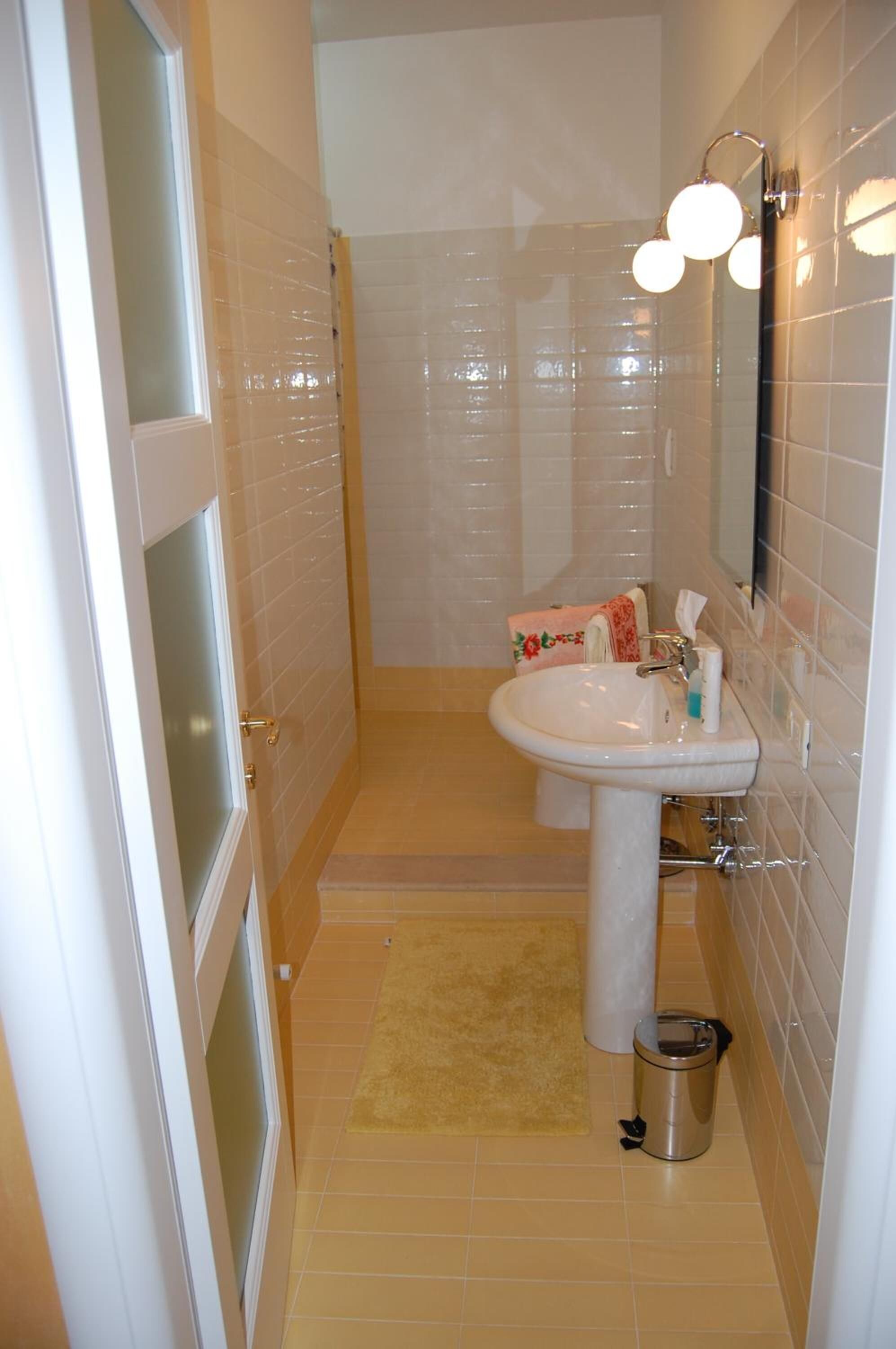 Ein kleines Badezimmer mit Waschbecken, Spiegel und Handtuchhalter.