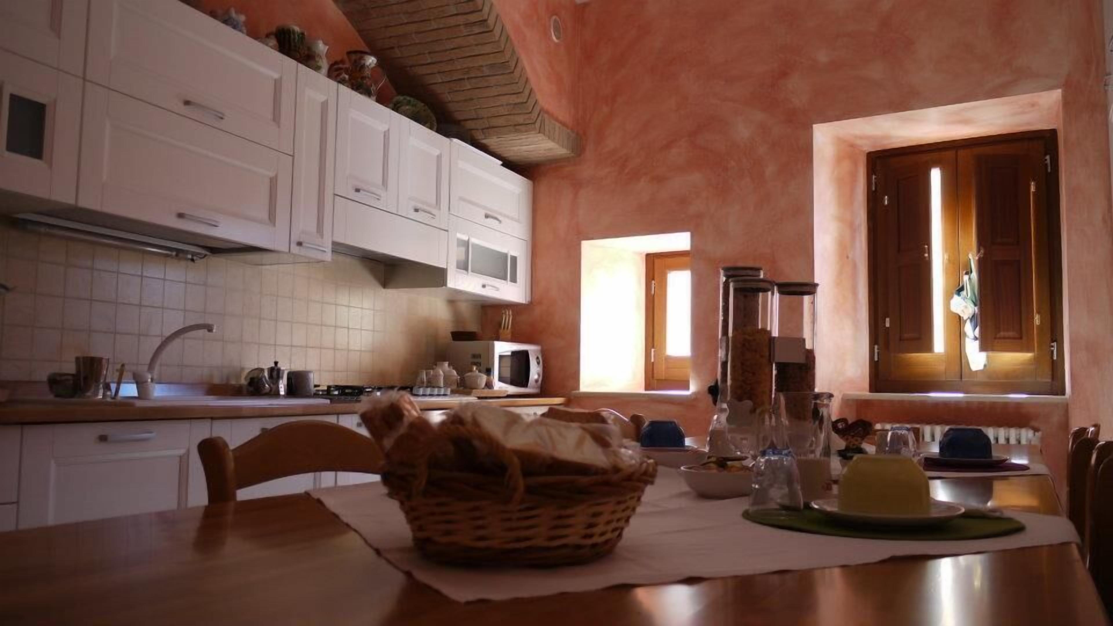 A kitchen with white cabinets, a microwave, and a window with curtains.