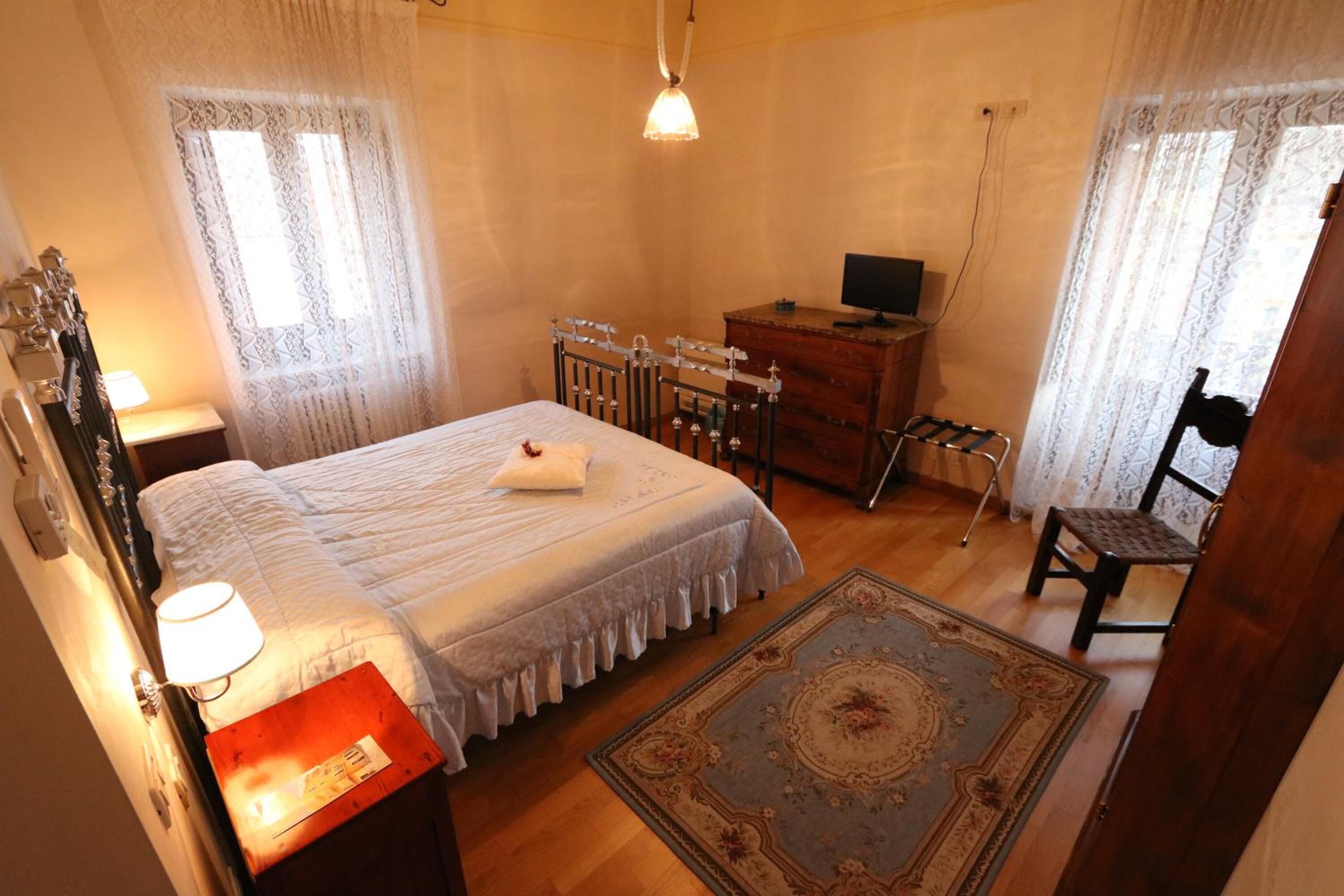 Un dormitorio con cama, cómoda, silla y escritorio con computadora.