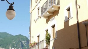 Un edificio amarillo con balcón, una farola y una montaña al fondo.