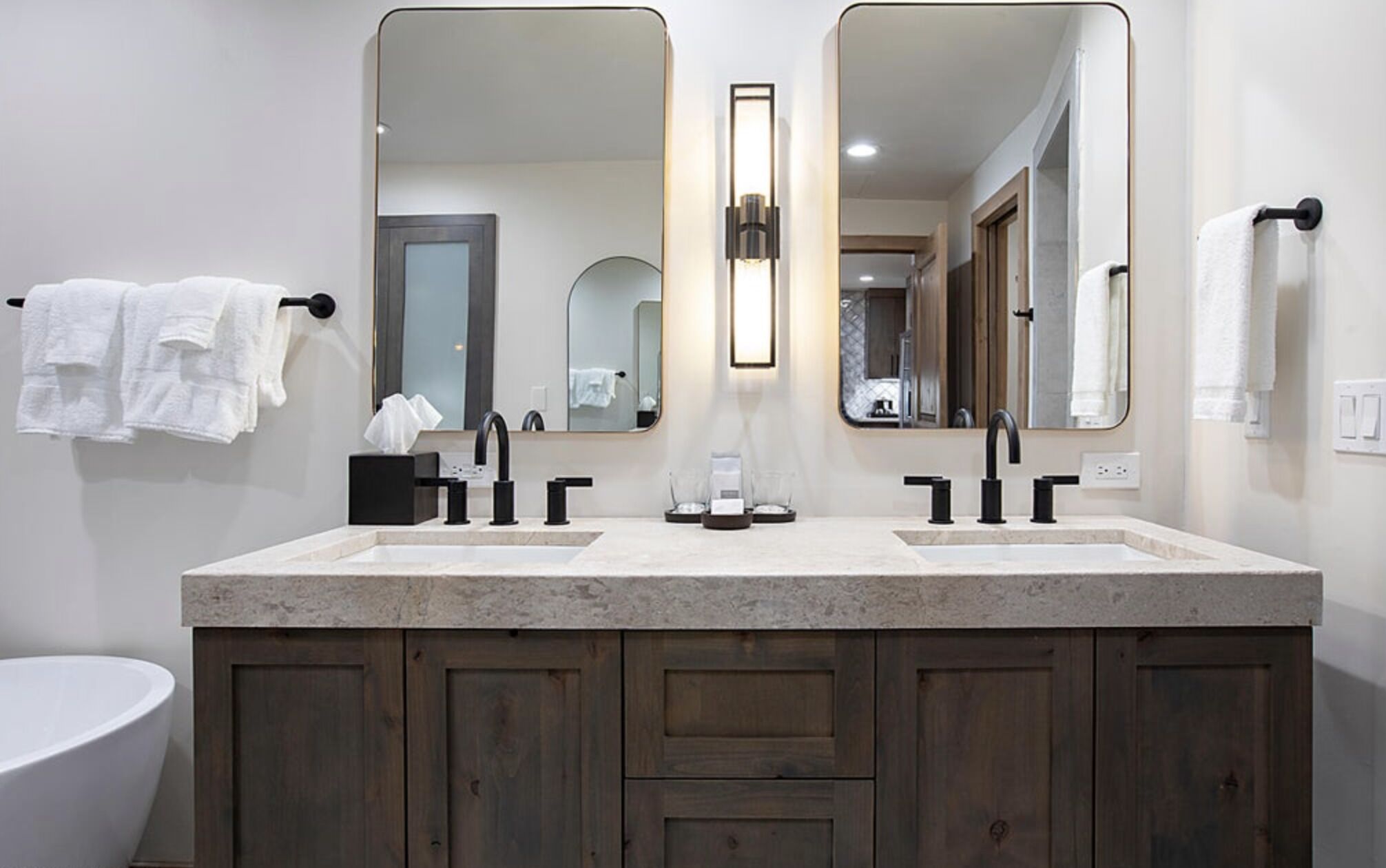 A modern bathroom with a double sink vanity, two mirrors, and a large mirror above the vanity.