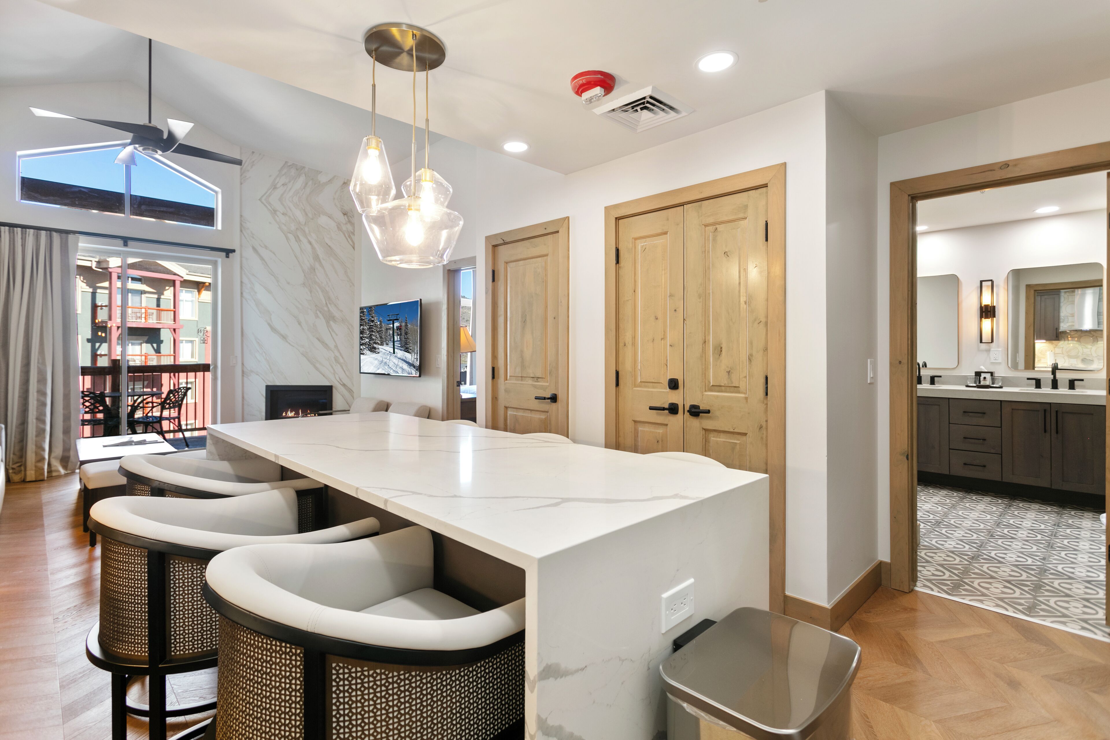 Una cocina moderna con una isla grande, taburetes de bar, puertas de madera y vistas al comedor.