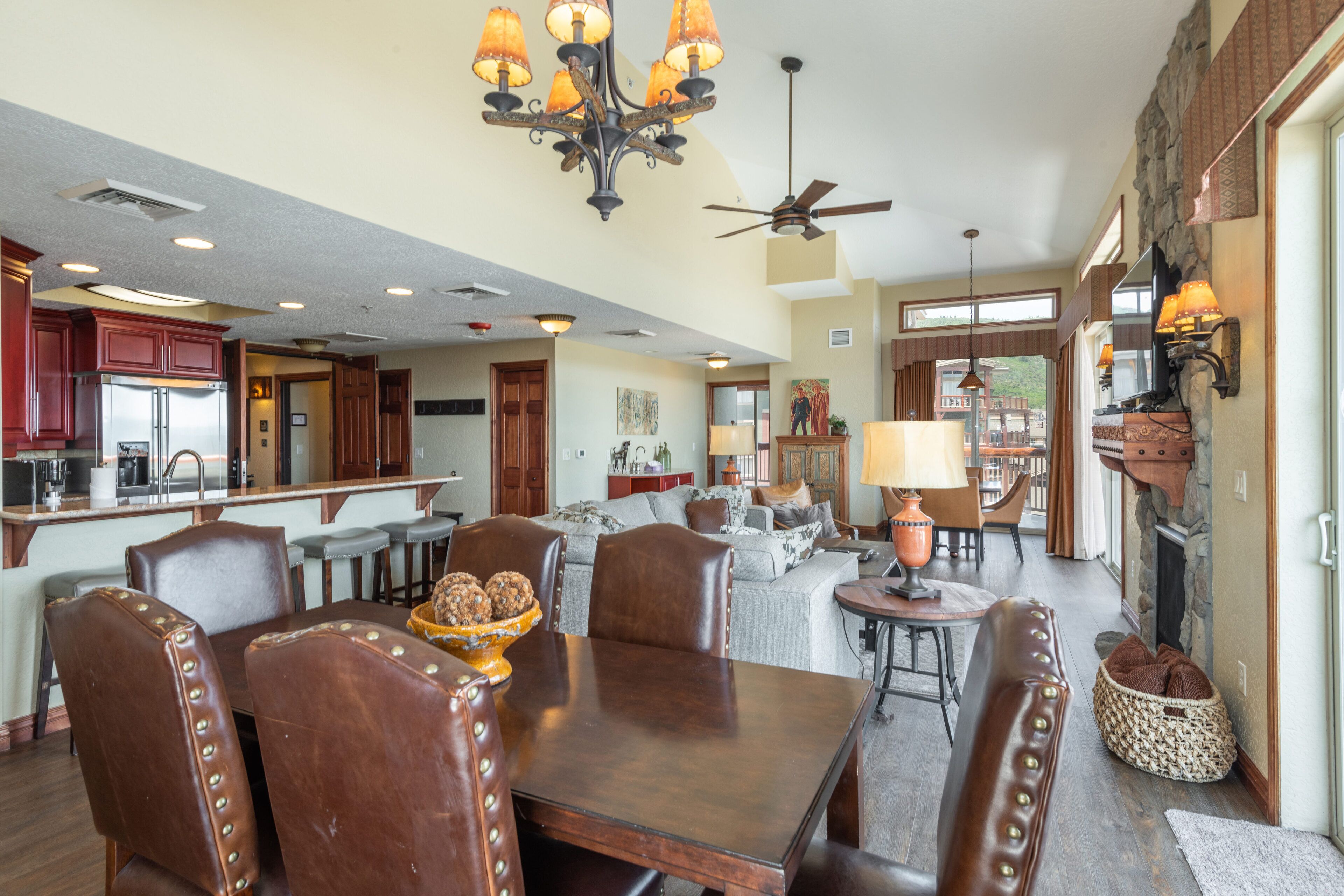 A spacious kitchen with a central island, a dining area with leather chairs, and a cozy living room with a fireplace.