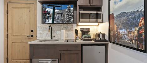 A compact kitchen with a built-in dishwasher, a microwave, and a large window above the sink.
