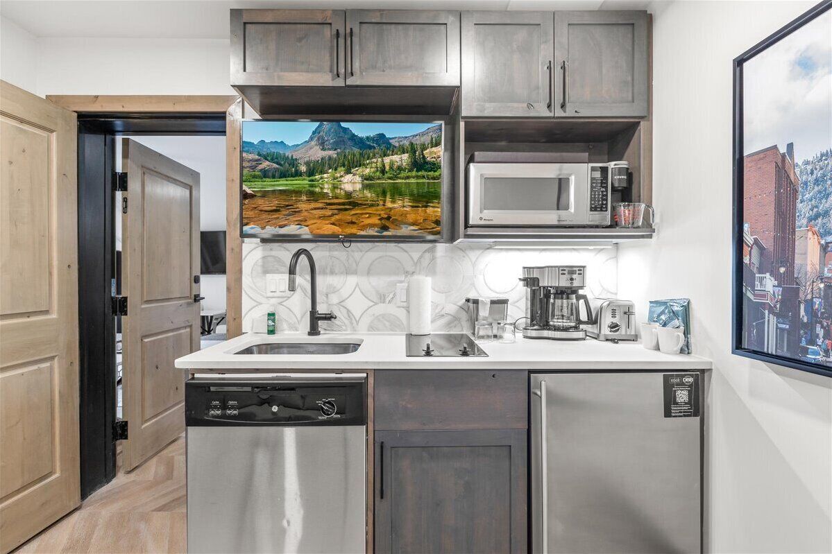 A modern kitchen with a built-in microwave, coffee maker, and dishwasher.